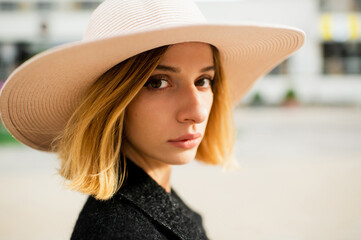 Close up portrait of elegant stylish blonde short hair girl in hat posing over street background