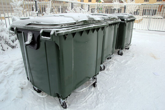 Garbage cans under the snow. Garbage removal. Cleaning. Janitor work.