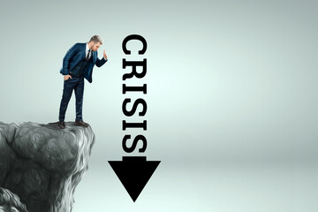 A man in a business suit stands on the edge of a cliff and looks down into an arrow with the...