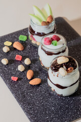 Sweet tasty milk curd creamy food in a glass jar of homemade breakfast. Cheesecake, English Trifle, Eton dessert, tiramisu, zuppa Inglese with nuts, almonds, cashews, hazelnuts, candied fruits
