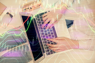 Obraz premium Double exposure of woman hands working on computer and forex graph hologram drawing. Top View. Financial analysis concept.