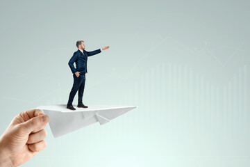 Startup. Businessman flying on a paper airplane with the pushing hand of an investor. Concept for opportunities, investments, business trends, business angels.