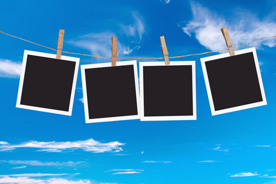 Four blank instant photo frames hanging on a rope, on blue sky background