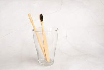 Bamboo toothbrushes in transparent glass on a marble background in the bathroom. Oral care concept. Natural organic bathroom cosmetic product concept. No plastic waste. copy space for text