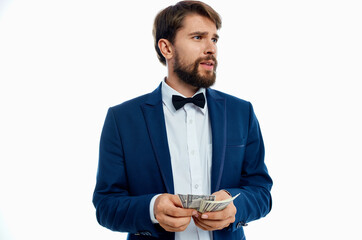 a rich man in a classic suit on a light background with a bundle of money in his hands