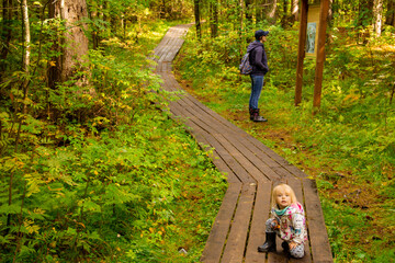 Mother and daughter are traveling. Mother and daughter are walking along the path of the nature reserve in the forest.