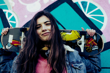 Girl with skateboard graffiti wall background