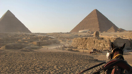 Obraz na płótnie Canvas Donkey ride through busy desert full of people viewing Pyramids Cairo Egypt
