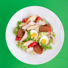 Caesar salad on a white plate on a green background. close-up. photo for clipping. for the menu