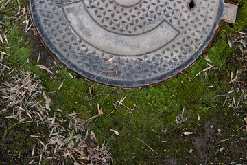 Green moss and old manhole. Grunge background.