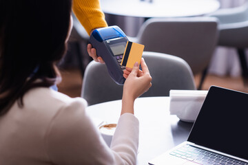 partial view of freelancer paying with credit card through payment terminal in restaurant