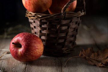 Red apple near a basket on a rustic table