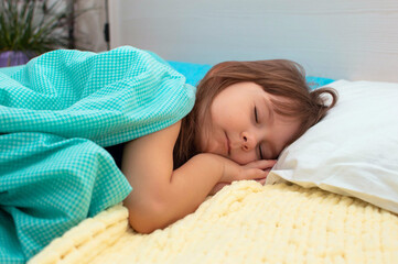 Sleeping little blonde close-up in big bed in early morning. Children dream. Childhood, peace, night .