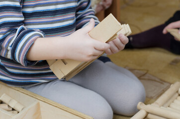 Obraz premium Child plays with wooden constructor in the room