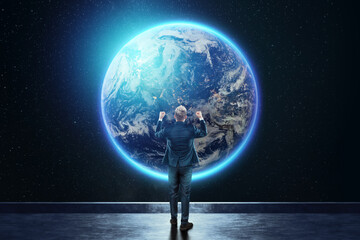 A man in a business suit, a businessman stands against the background of the globe. Mixed media. Concept Global networks and international business. Elements of this image furnished by NASA.