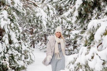 Beautiful young scandinavian caucasian woman on a walk in the forest in winter, among the snowy pine trees
