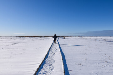 Man walking on a trail in an open winter landscape