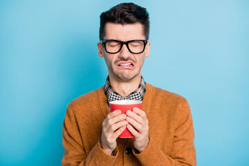 Photo of unhappy sad man drink bad coffee dislike morning wear glasses isolated on pastel blue...