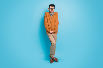 Full size photo of shy modest young nerd guy make timid pose hold hands together isolated on blue...