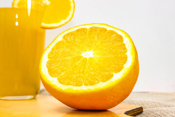 A sliced half of a ripe orange and a glass of juice in the background.