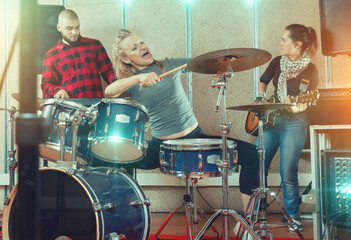 Rehearsal of the music group. Rock band with emotional female drummer playing in recording studio