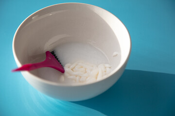 On the table is a bowl with hair dye and a brush. Home coloring concept.