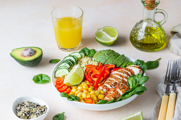 Healthy buddha bowl lunch with grilled chicken and bulgur, spinach, avocado, cucumber, bell pepper and corn on concrete background. Delicious balanced food concept.
