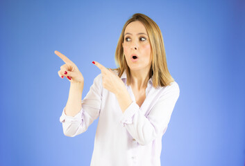 Portrait of beautiful young woman pointing up over purple background.