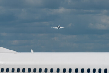 A modern white jet airliner takes off from the airport against the backdrop of a cloudy sky.