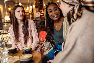 Three young multi ethnic women enjoy coffee at a coffee shop