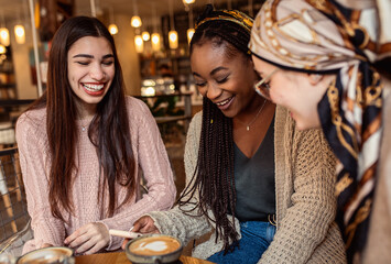 Three young multi ethnic women enjoy coffee at a coffee shop