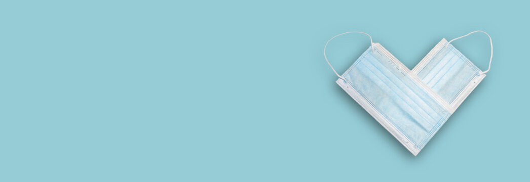 Banner with two medical face masks set to form a heart, at solid background with copy space, closeup, details. Concept of prevention measures against coronavirus pandemic outbreak.