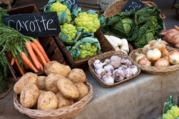 Vegetables for sell in vintage french street market. Potatoes, carrots,green cauliflower,garlic, onions and cabbage in baskets.