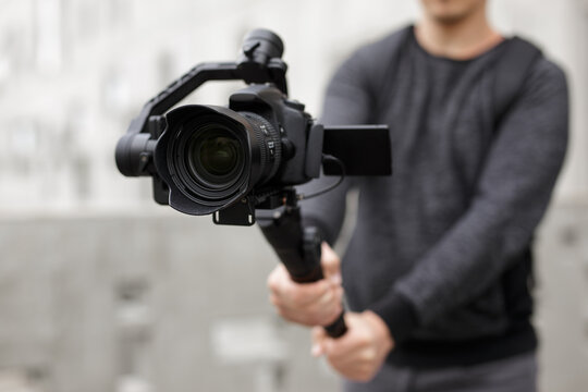 filmmaking, hobby and creativity concept - close up of modern dslr camera on 3-axis gimbal in male hands