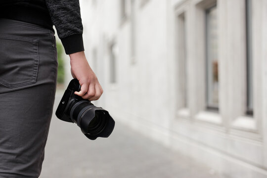 modern dslr camera in male hands, copy space over concrete building background