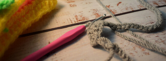 On rustic table, crochet and wool utensil to create handmade garments