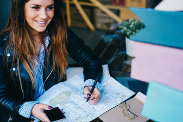 Woman with map and smartphone at table