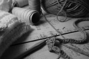 On rustic table, bobbin of threads and wool, to create patterns and handmade crochet garments