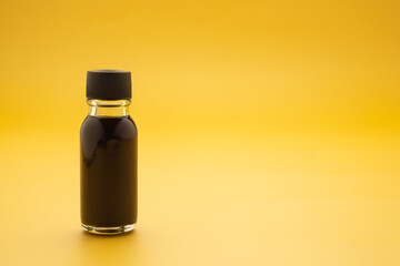 The essential oil in a bottle placed on a yellow background. Space for text. Side view photo