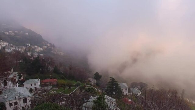 PAN SHOT IN MAKRINITSA VILLAGE GREECE WITH FOG AND WARM LIGHT DURING SUNSET 