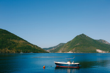 A blue fishing wooden boat moored in the Bay of Kotor near the town of Perast in Montenegro.