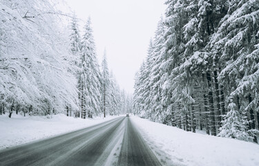 Fototapeta premium A road on the background of a beautiful winter snow-covered landscape.Family trip, vacation, adventure. Driving a car in extreme winter conditions.Travel concept background