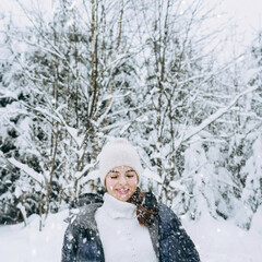Fototapeta na wymiar Young happy girl is enjoying the winter on a frosty day, with snow playing with snow in winter Park.The winter lifestyle.Individual winter adventures.Rest during the Christmas holidays.healthy break