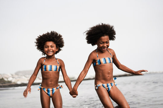 Happy african sister twins running on the beach together - Main focus on right girl