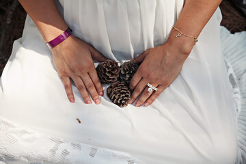 A pregnant woman in a white dress holding three cones