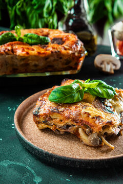 A piece of vegetarian lasagna with mushrooms, tomatoes and basil on the plate vertical photo