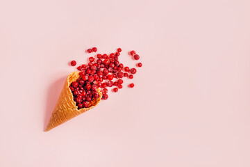 top view of a waffle cup filled with currants on a pink background