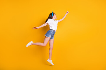 Fototapeta na wymiar Full length body size photo of childish girl jumping high touching looking at blank space isolated on bright yellow color background