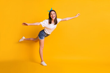 Fototapeta na wymiar Full length body size view of pretty glad slim cheerful girl having fun flying like plane isolated over vivid yellow color background
