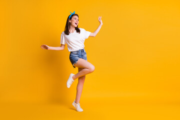 Full length body size view of skinny dreamy cheerful brown-haired girl jumping dancing isolated over bright yellow color background